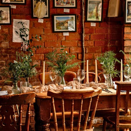 Wedding reception table styling with candles and greenery at the venue